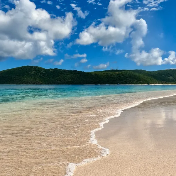 a sandy beach next to a body of water