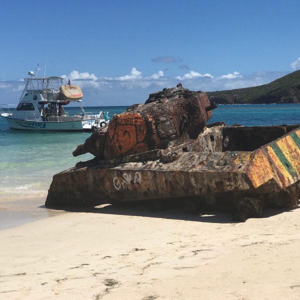 a boat that is sitting on a rock next to a body of water