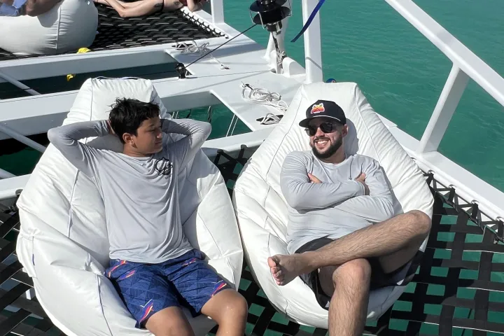 a group of people sitting on a bench next to a body of water